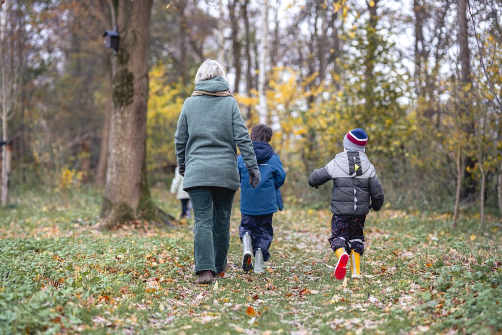 Leerkracht loopt met kinderen door het bos